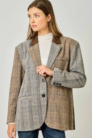Woman wearing a plaid blazer with a neutral background