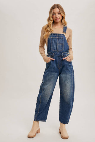 Woman wearing blue denim overalls on a plain background
