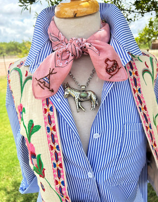 Mannequin wearing a blue striped shirt with a pink embroidered scarf outdoors.