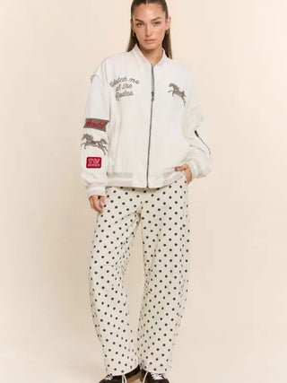 Cream bomber jacket with western rodeo embroidery and patches, worn over polka dot pants
