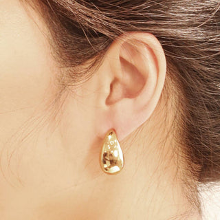 14K gold polished teardrop stud earring worn on ear, smooth domed finish