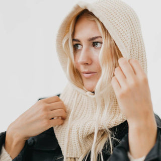 Woman wearing cream knit hooded balaclava scarf over black jacket