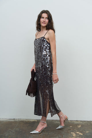 Model wearing a dark brown large sequin spaghetti strap midi slip dress with silver heels