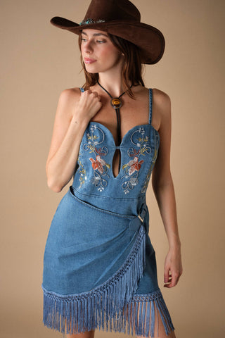 Model wearing embroidered denim mini dress with fringe hem, keyhole bodice, and cowboy hat