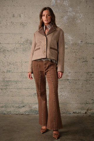Woman wearing a two-tone wool jacket with embroidery detail and fringe hem trim