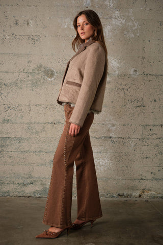 Model wearing a two-tone wool jacket with embroidery detail and contrasting trim, side view