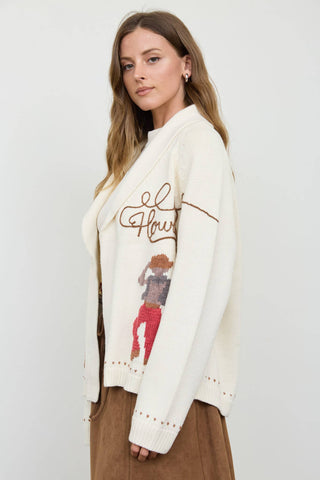 Cream knit cardigan with Howdy script and cowgirl jacquard graphic, shawl collar
