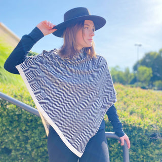 Black and white herringbone knit poncho with cream trim, worn outdoors