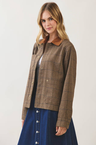 Model wearing a brown plaid chore jacket with corduroy collar over a blue denim skirt