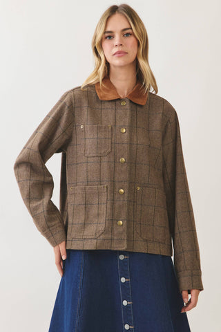 Woman wearing a brown plaid chore jacket with gold snap buttons and contrast collar