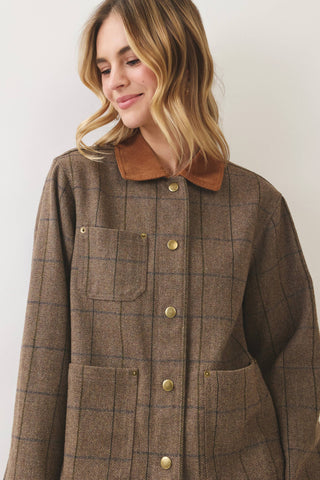 Woman wearing an oversized brown plaid chore jacket with gold snap buttons and corduroy collar