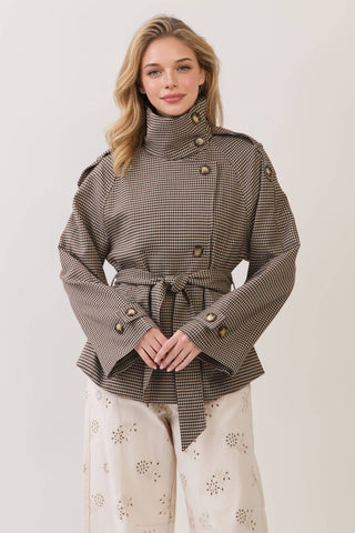 Model wearing cropped plaid trench coat with gold buttons, epaulettes, and tie waist belt