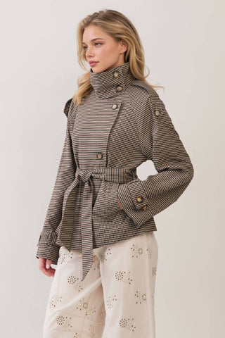 Model wearing a cropped plaid trench coat with belt, button details, and high collar