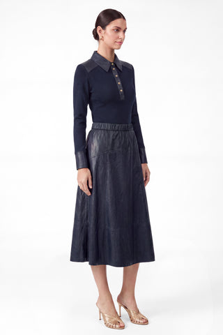 Model wearing a navy PU leather A-line midi skirt with elasticized waist and flared hem