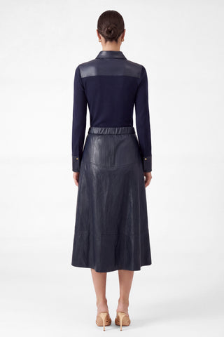 Back view of model wearing navy PU leather elasticized waist A-line midi skirt with paneling