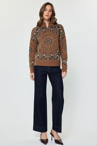 Model wearing a caramel paisley jacquard half-zip long sleeve sweater with wide-leg dark jeans