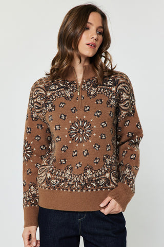 Woman wearing a caramel paisley jacquard half-zip long sleeve pullover sweater with dark jeans