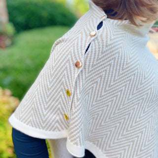 Beige herringbone knit poncho cape with gold snap buttons on shoulder seam