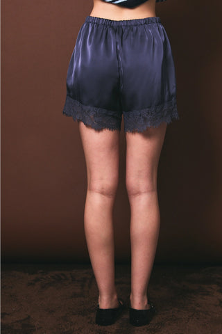 Midnight blue satin shorts with black lace trim hem and elastic waist, back view