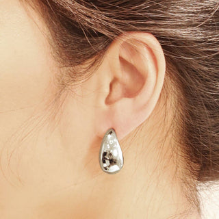 Silver teardrop solid stud earring worn on ear, polished finish