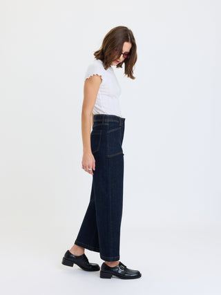 Model wearing high-rise wide-leg ankle denim jeans with patch pockets, side profile view