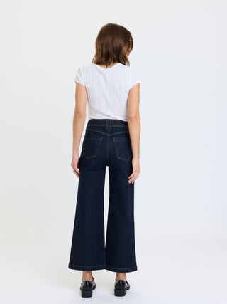 Back view of wide-leg ankle jeans with patch pockets worn with white crop tee