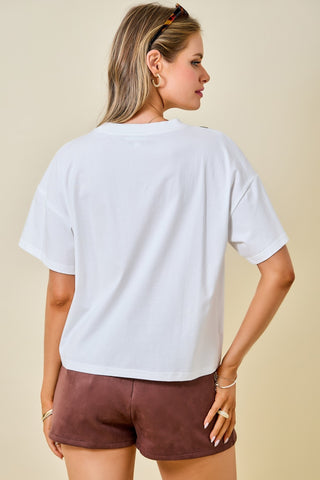 Oversized white crop tee with short sleeves, worn with brown shorts, back view.
