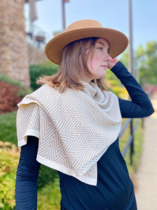 Tan and ivory chevron knit poncho draped over shoulders, white trim edges