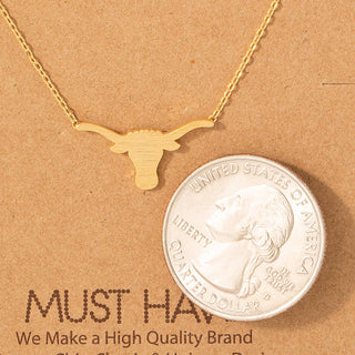 Dainty gold longhorn bull head pendant necklace shown next to quarter for scale