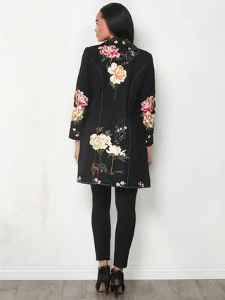 Back view of a black longline duster jacket showing large floral embroidery in pink, cream, and green across the back