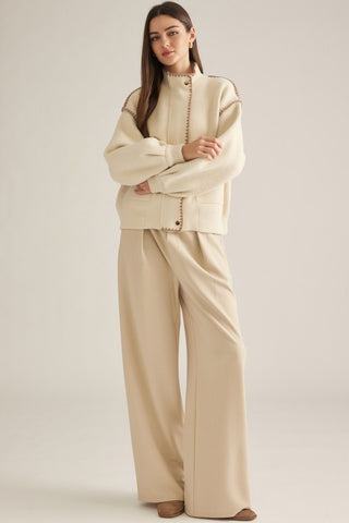 Cream oversized fleece jacket with brown whipstitch trim and wide-leg trousers