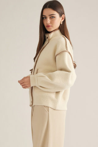 Cream oversized cardigan with brown whipstitch trim, mock neck, and button front