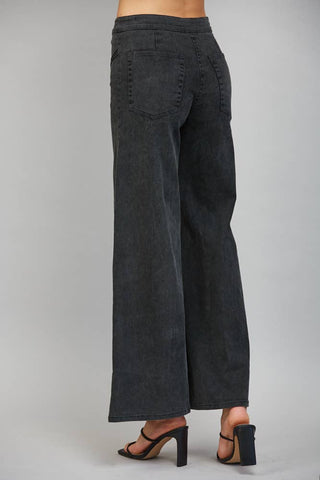 Back view of wide-leg high-waisted flare jeans with back pocket detail on model wearing heels
