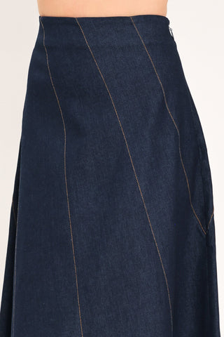 Close-up detail of dark indigo denim midi skirt showing diagonal seams and side zipper closure