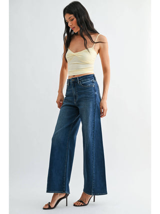 Model wearing high-rise wide-leg dark wash jeans with cropped camisole and heeled sandals