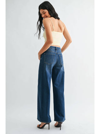 Back view of wide leg high-rise dark wash jeans paired with cream crop top and heels
