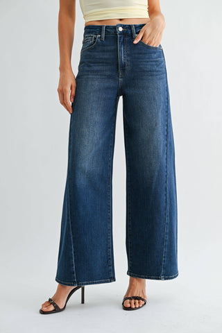High-rise wide-leg dark wash jeans styled with strappy heels and cream crop top