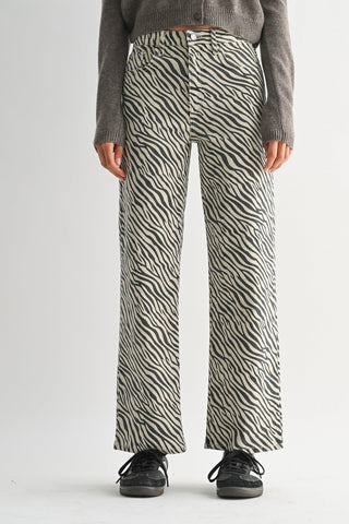 Wide-leg straight trousers in zebra stripe print worn with grey knit sweater and sneakers