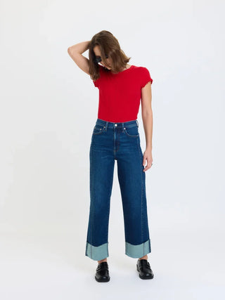 Model wearing high rise wide ankle jeans with contrast cuffed hem and black loafers