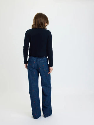 Back view of model wearing fitted navy cardigan with wide-leg embroidered jeans