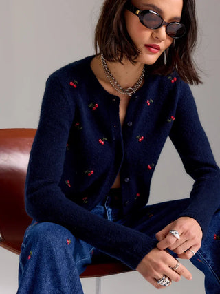 Model wearing navy fitted cardigan with scattered cherry embroidery, paired with denim jeans