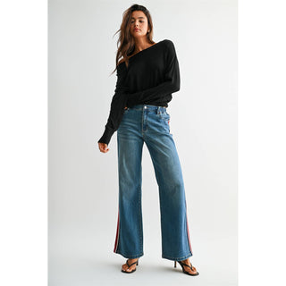 Model wearing high-rise wide leg jeans with red and white side stripe detail, paired with black off-shoulder top