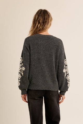 Back view of ladies knitted sweater with floral embroidered sleeves on female model