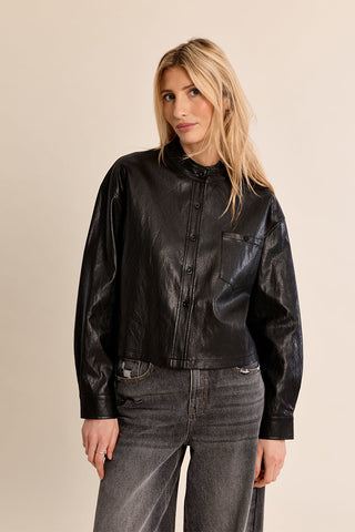Woman wearing a black faux leather button-front overshirt with chest pocket and long sleeves
