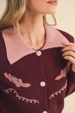 Burgundy western cardigan with pink collar, embroidered details, and pom-pom trim