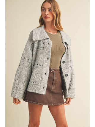 Model wearing an oversized heather grey eyelit knit cardigan sweater with button front and collar