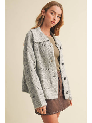 Model wearing an oversized heather grey eyelit knit button-front cardigan sweater with collar