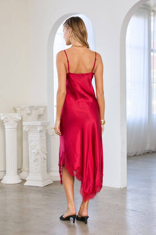 Model wearing a red satin midi slip dress with lace hem trim and spaghetti straps, back view