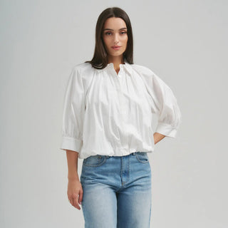 Woman wearing a white blouse and blue jeans on a gray background