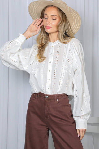 Model wearing white cotton eyelet blouse with long puff sleeves, paired with brown wide-leg pants